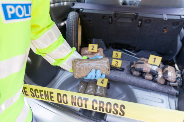 Crime scene: Drug smuggling Police officer holding drug package discovered in the trunk of a car organized crime photos stock pictures, royalty-free photos & images