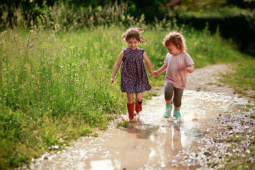 Smiling girls playing in muddy water.