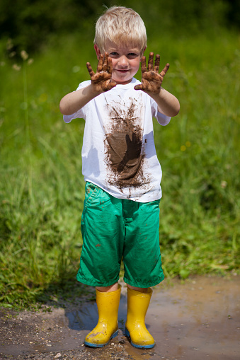 Portrait of boy playing in mud outdoors.