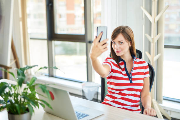istock Female employee sitting in office and taking selfie. 1089349054