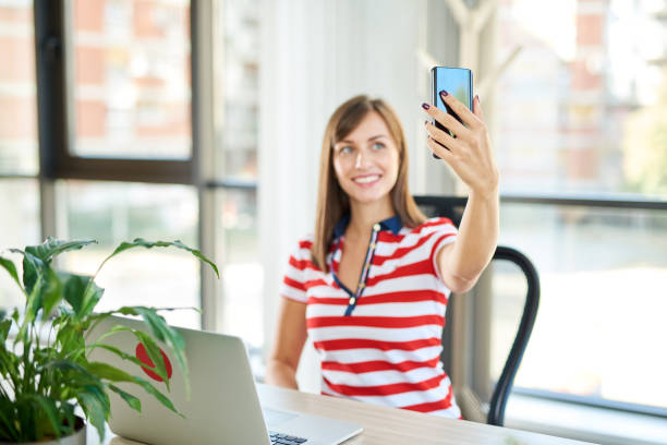 istock Female employee sitting in office and taking selfie. 1089349094