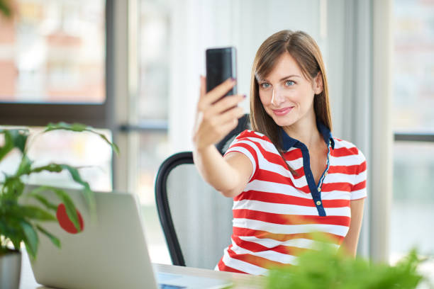 istock Female employee sitting in office and taking selfie. 1089349128