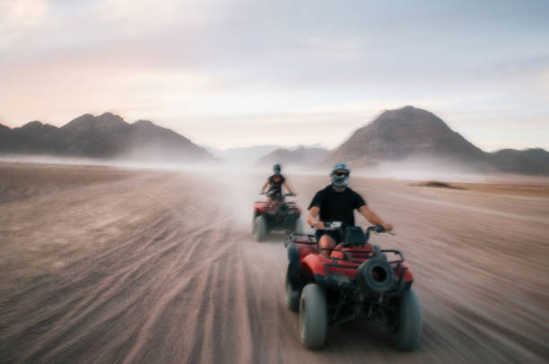 Buggy and ATV quads races in Sinai desert at sunset, Egypt. Buggy and ATV quads races in Sinai desert at sunset. Egyptian landscape with off-road vehicles and dust dirt road. Sharm el Sheikh, Egypt. Defocused motion blur desert safari stock pictures, royalty-free photos & images