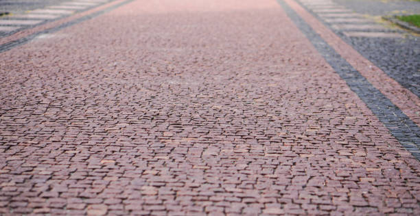 callejones de adoquines viejos, caminos. textura del pavimento de adoquines de color rojizo. fotografía de stock - paving stone avenue stone curve fotografías e imágenes de stock