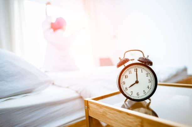 istock Closeup alarm clock in bed after waking up, sunlight in morning. 1089382282