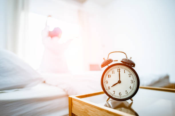 istock Closeup alarm clock in bed after waking up, sunlight in morning. 1089382284