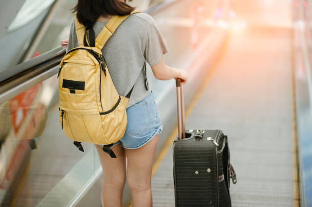 istock Young woman pulling and use smartphone suitcase in modern airport terminal. Travelling guy with his luggage while waiting for transport. Rear view. Copy space 1089383800