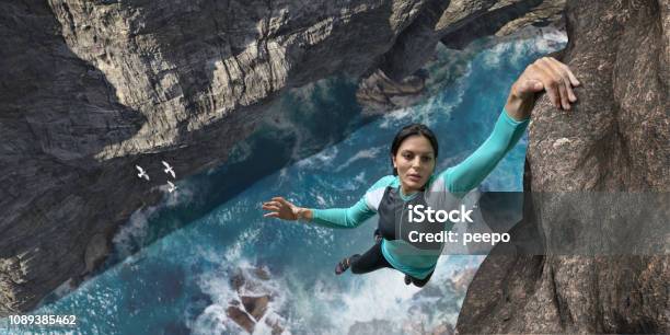 Free Climber Hangs One Handed On Sea Cliff Rock Face Stock Photo - Download Image Now