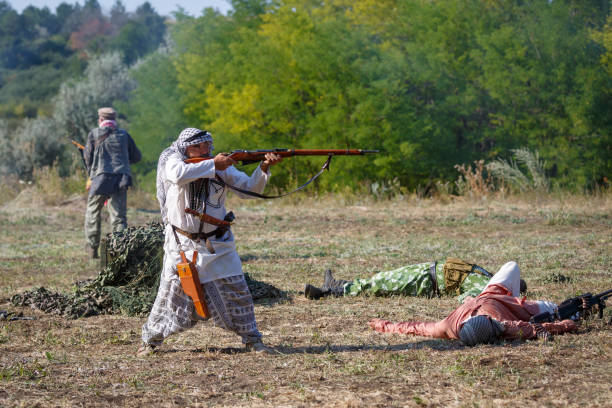 mojahed stands and shoots a rifle - jihad imagens e fotografias de stock