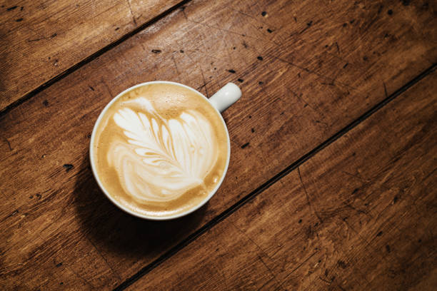 Overhead Flat White Coffee against an aged wood background.