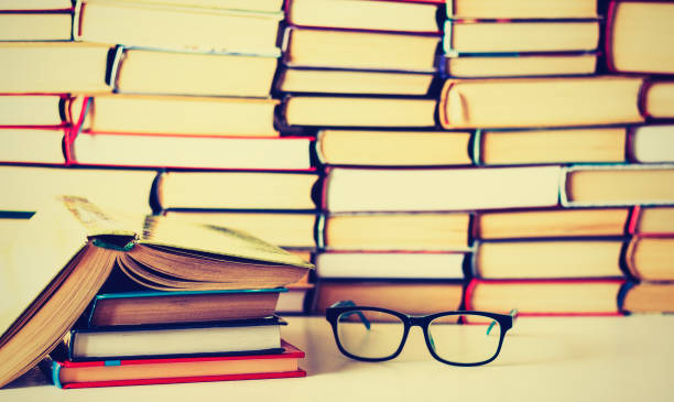 istock Hardback books on white wooden table, open book and glasses, copy space for text 1089392472