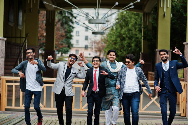 Group of six south asian indian mans in traditional, casual and business wear walking dancing and having fun together.
