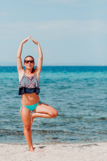 istock Young woman doing yoga on the beach 1089406122