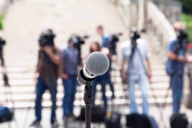istock Microphone in focus against blurred camera operators and journalists at news conference 1089411424