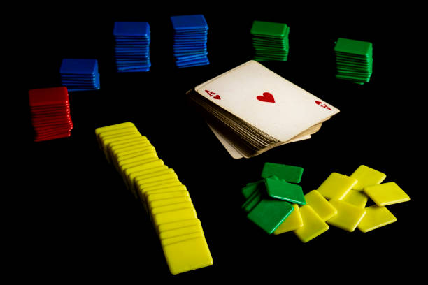 old deck of poker cards next to colored plastic chips on a black background