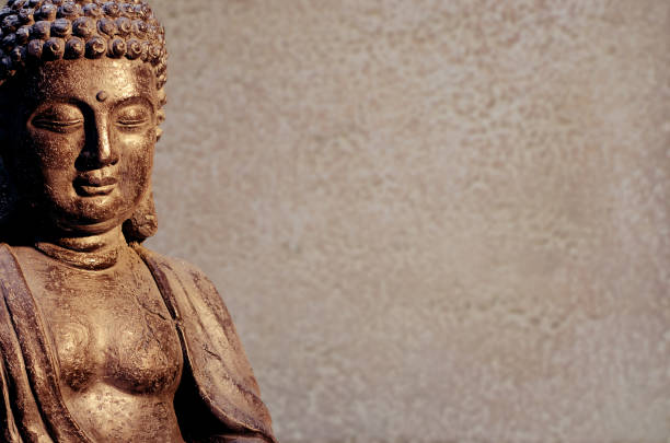 istock Buddha statue sitting in meditation pose against blurred golden background. 1089426434