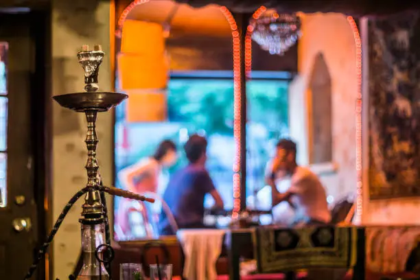 A defocused scene of a small group of friends socializing at a hookah bar & lounge