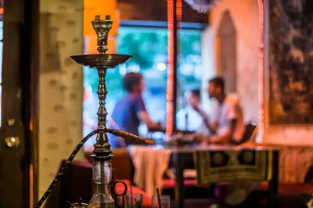 A defocused scene of a small group of friends socializing at a hookah bar & lounge