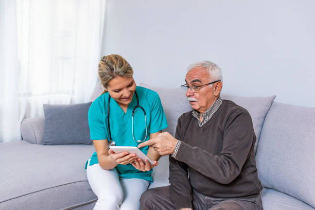 istock Young caregiver watching movie on tablet with old man while sitting on sofa 1089457634