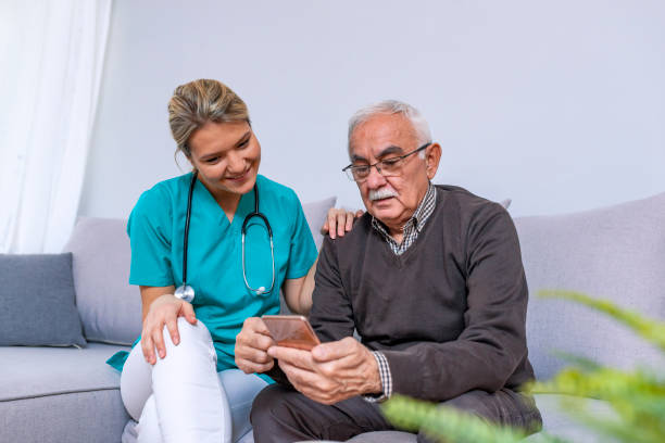 istock Carer and senior man with tablet sitting on the sofa 1089457848
