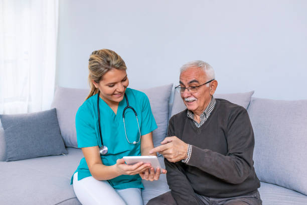 istock Carer and senior man with tablet sitting on the sofa 1089458212
