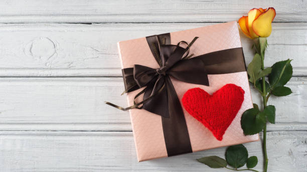 istock orange rose and gift on white table with heart 1089458490