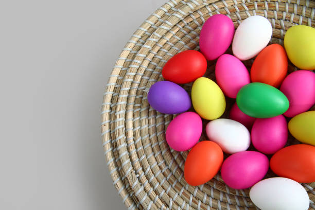 istock Brightly colored easter eggs, in a straw basket against a grey background. 1089463932