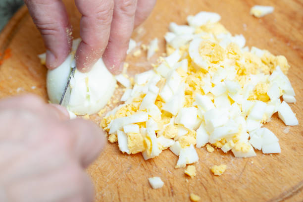 uova di gallina sode affettate sulla tavola da cucina. preparazione dell'ingrediente per il piatto. cucina fatta in casa. - hard cooked egg foto e immagini stock