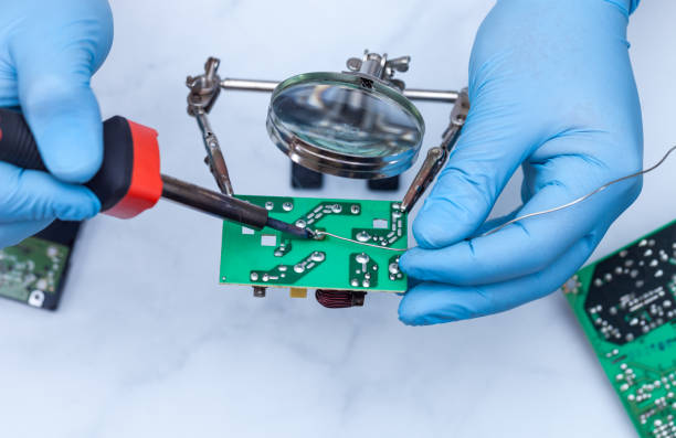 istock Hands wearing gloves solders and verifies computer circuit board using soldering iron and multimeter 1089487110