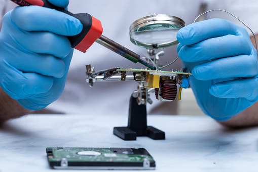 Hands Wearing Gloves Solders And Verifies Computer Circuit Board Using Hands Wearing Gloves Solders And Verifies Computer Circuit Board Using