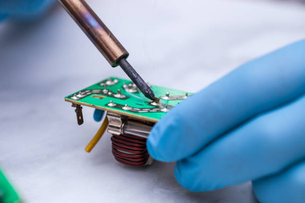 istock Hands wearing gloves solders and verifies computer circuit board using soldering iron and multimeter 1089487466