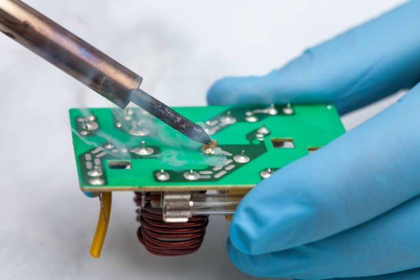istock Hands wearing gloves solders and verifies computer circuit board using soldering iron and multimeter 1089487512