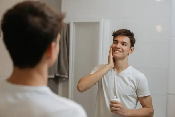 man putting after shave lotion on his face