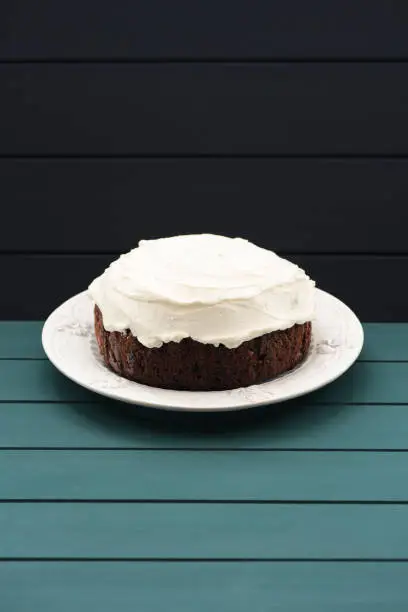 Minimalist style sweets. Chocolate fruit cake with cream cheese glasing on dark background copyspace