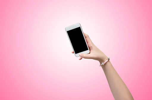 Female hand holding a smartphone over pink background
