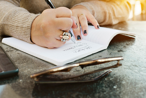 View of female hands writing her life goals in a journal