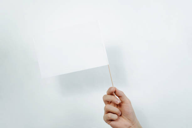 istock Hand holding a white flag on a light, white background. 1089519564