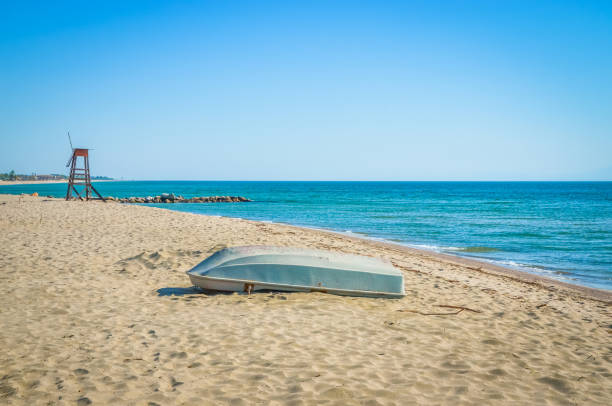 Donnalucata (Ragusa), Sicily: A beautiful blue and white striped rowboat/fishing boat on a winter beach nearing sunset. Shot on the southern coast of Sicily. Copy space available in the vibrant blue sky.