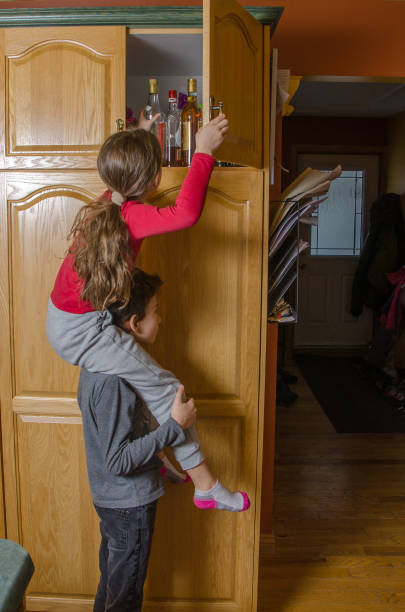 istock Girl reaching to alcohol bottles while sitting on her brother's shoulder as help 1089561688