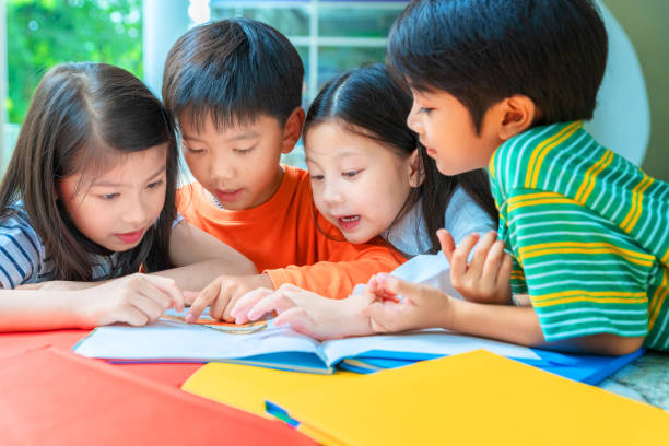 アジアの小さな子供たちが陽気な本を読んで - multi ethnic group teenage girls little boys child ストックフォトと画像