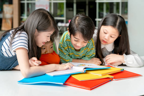 asiatische kleine kinder buch fröhlich - reading and writing little boys reading asian ethnicity stock-fotos und bilder