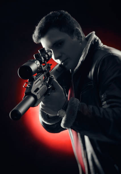 istock Young men with guns posing on a black background in backlit 1089572806
