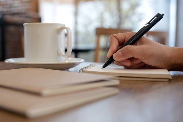 istock a hand writing on blank notebook with coffee cup on table in cafe 1089581696