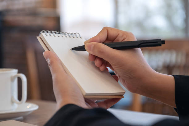istock a hand holding and writing on blank notebook with coffee cup on table in cafe 1089581754