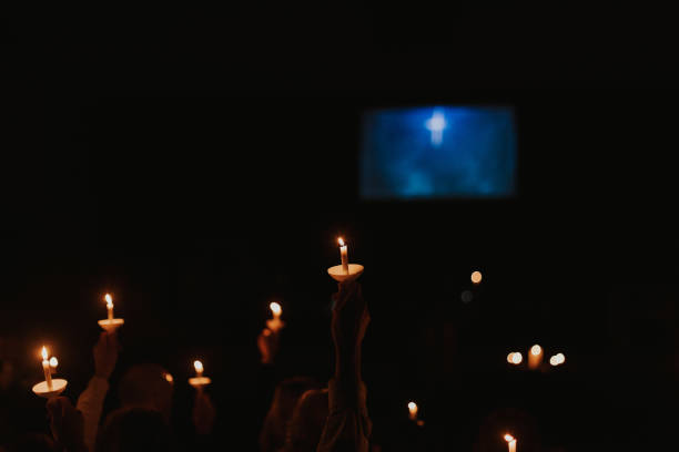 People holding candles and candles by themselves at a Christmas Eve church service or a vigil.