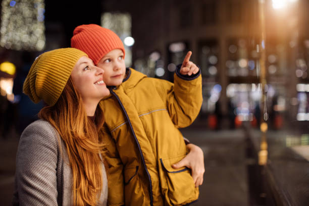 Boy with mother pointing at store window Sweet boy with mother pointing at store window at night window shopping at night stock pictures, royalty-free photos & images