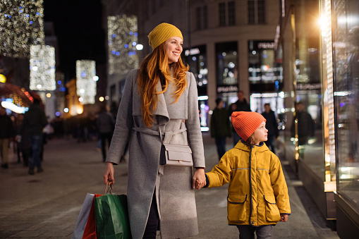 Mother and her child shop in a big city at night