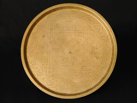 ancient oriental metal tray on dark background. antique bronze tableware