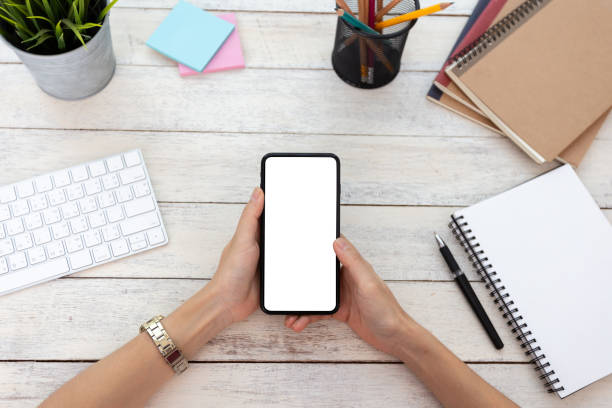 istock hand woman using a telephone, empty screen smart phone and computer on wooden table In home office. with clipping path 1089601544