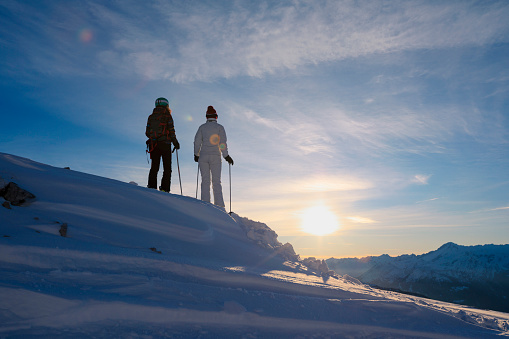 Friends skiing. Snow skiers skiing at sunny ski resort, sunset Dolomites mountain in Italy.